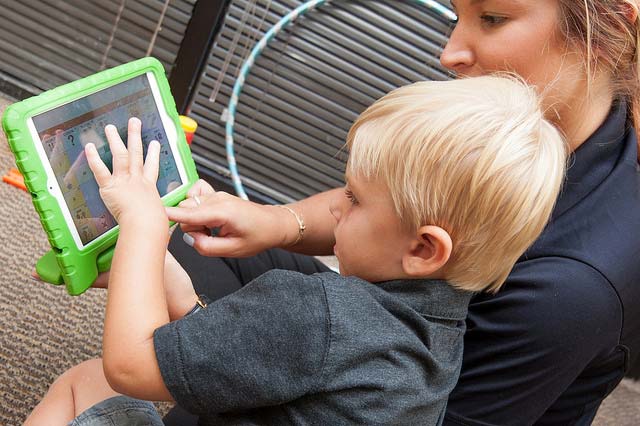 UCF student helping a child navigate an interactive tablet
