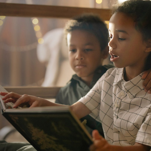 two children reading a book together