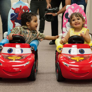 two kids sitting in go baby go cars
