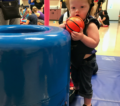 young child in a harness playing a game with a small