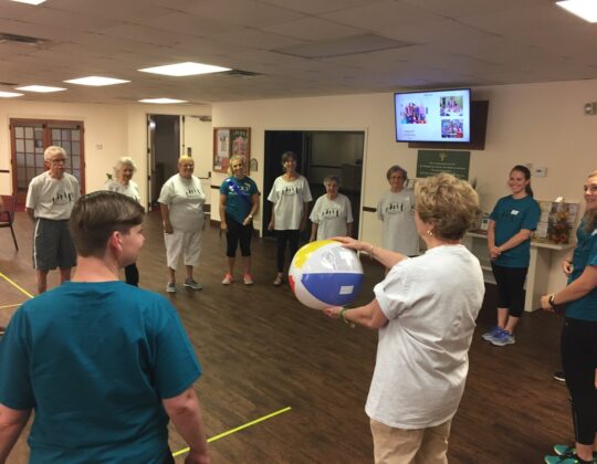 elderly participants playing a game where they pass a beach ball