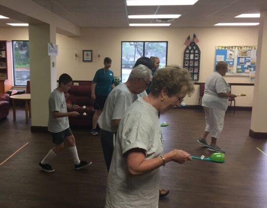 elderly participants playing a game where they carry a plastic egg with a spoon