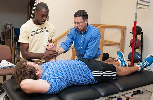 faculty and students examining another student in the PT Clinic