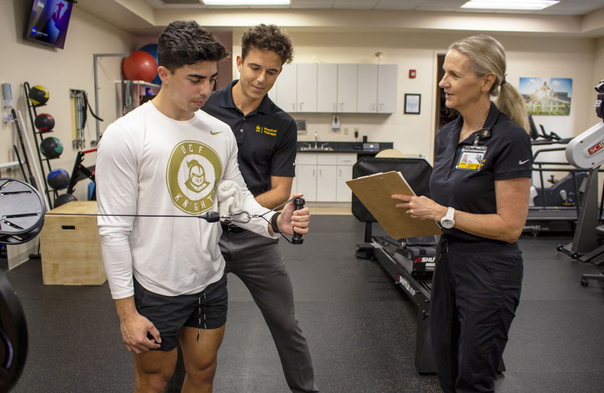 Physical Therapy Faculty and Student working with a student volunteer doing arm exercises