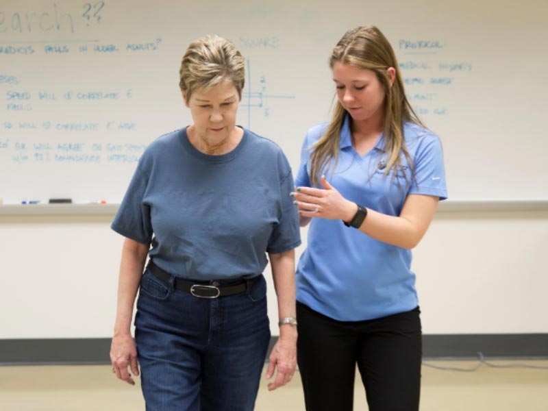 student in the iMoveLab assisting an elderly volunteer