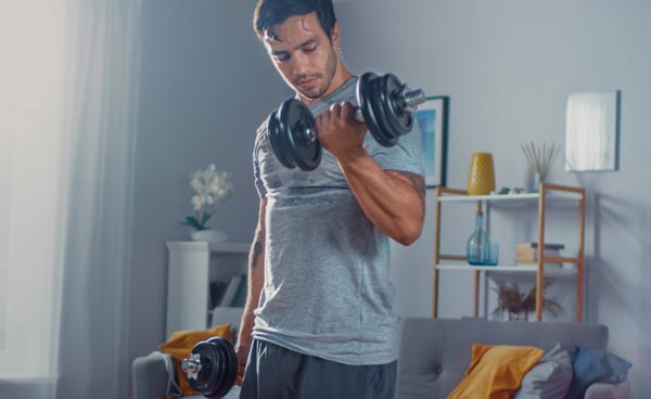 Male doing arm curls with free weights in his living room