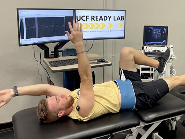 student in the UCF Ready Lab on his back moving his body with electrodes on
