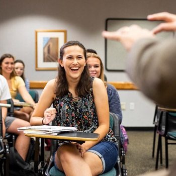 group of students sitting in desks laughing as the instructor gives his lesson