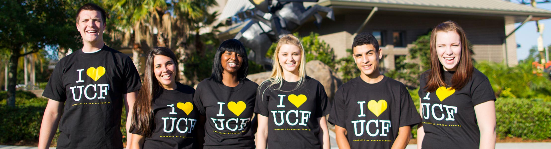 a group shot of UCF students standing a row smiling at the camera wearing I (heart) UCF tshirts