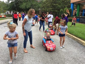 Parents, children and kids in modified ride-on toy cars gather together at the Go Baby Go! event.