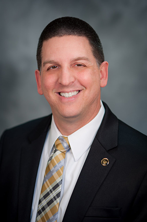 A professional man wearing a suit and tie and smiling