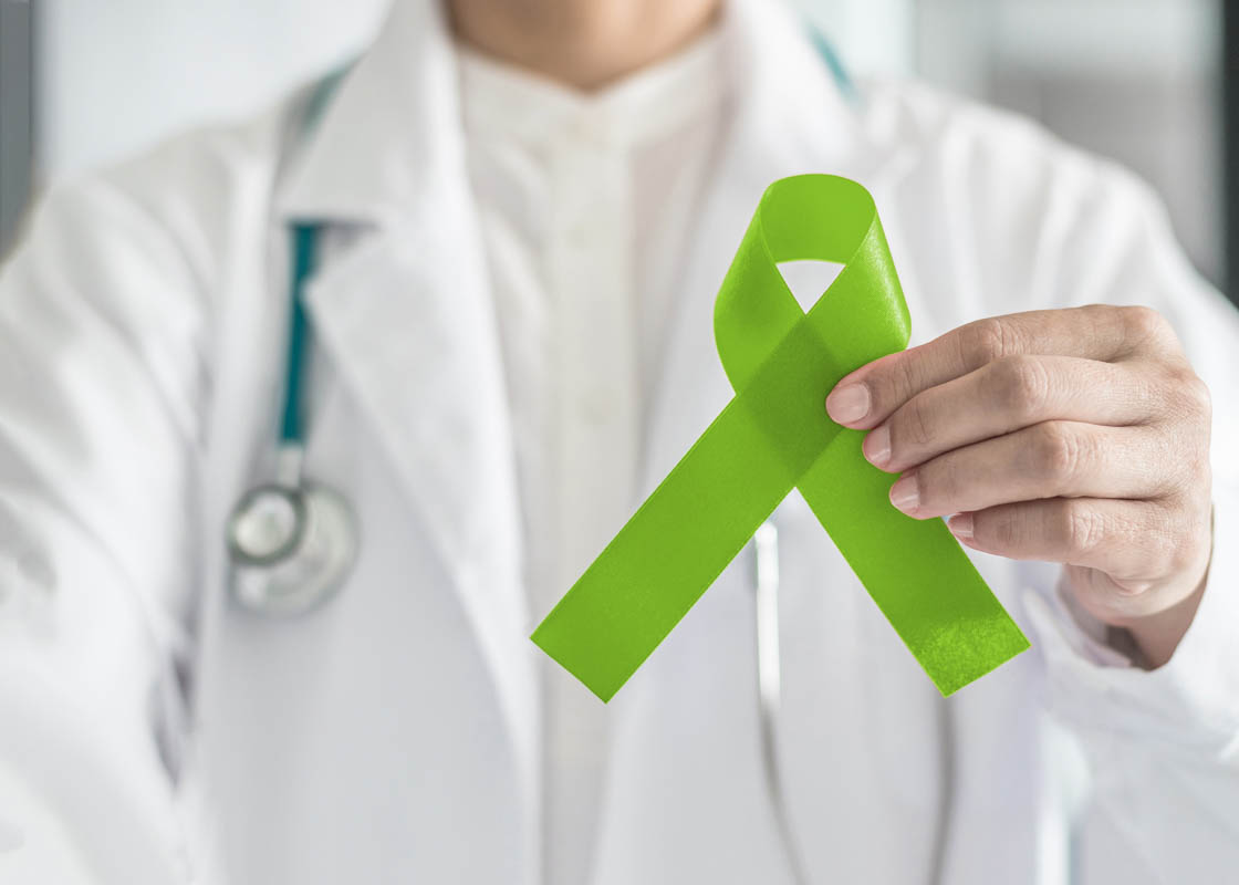 Medical professional holding a green ribbon, which represents mental health awareness.