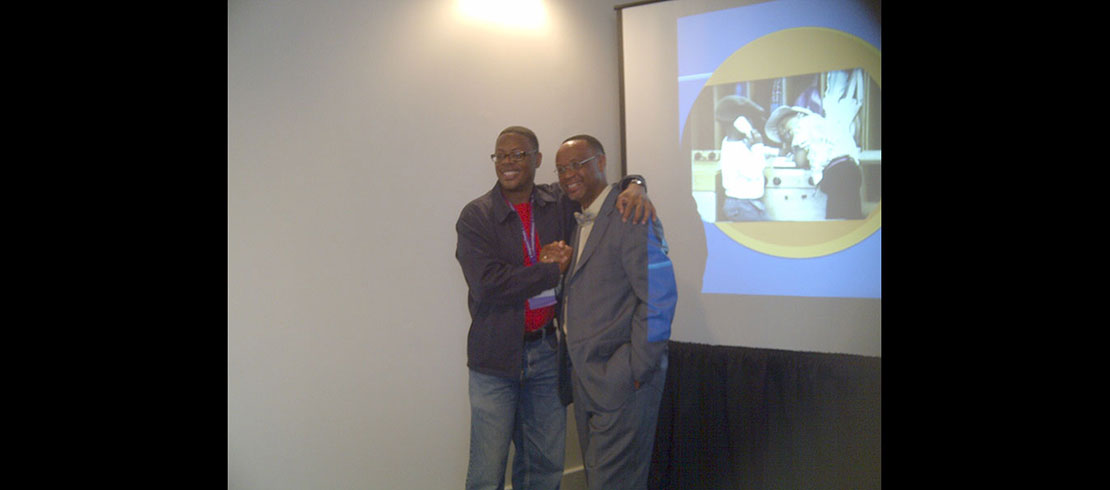 Kenyatta at a conference surrounded by a colleague