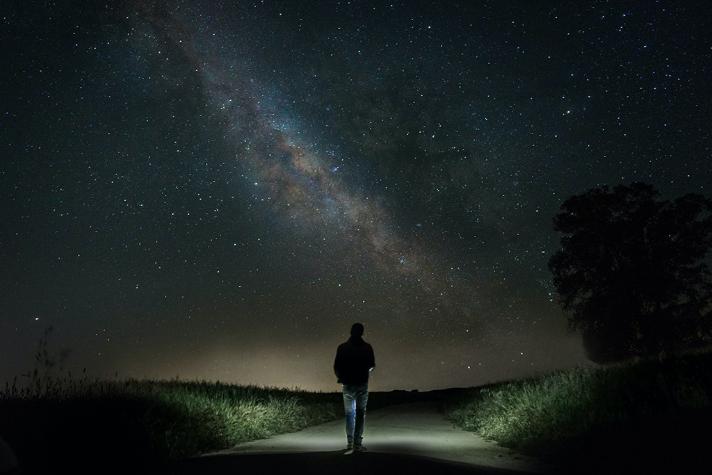 man walking outside at night looking up at the stars