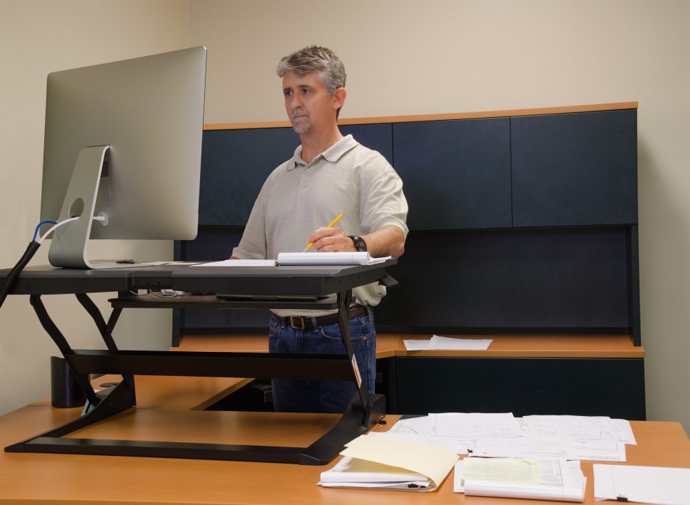A man using a stand-up desk in office.