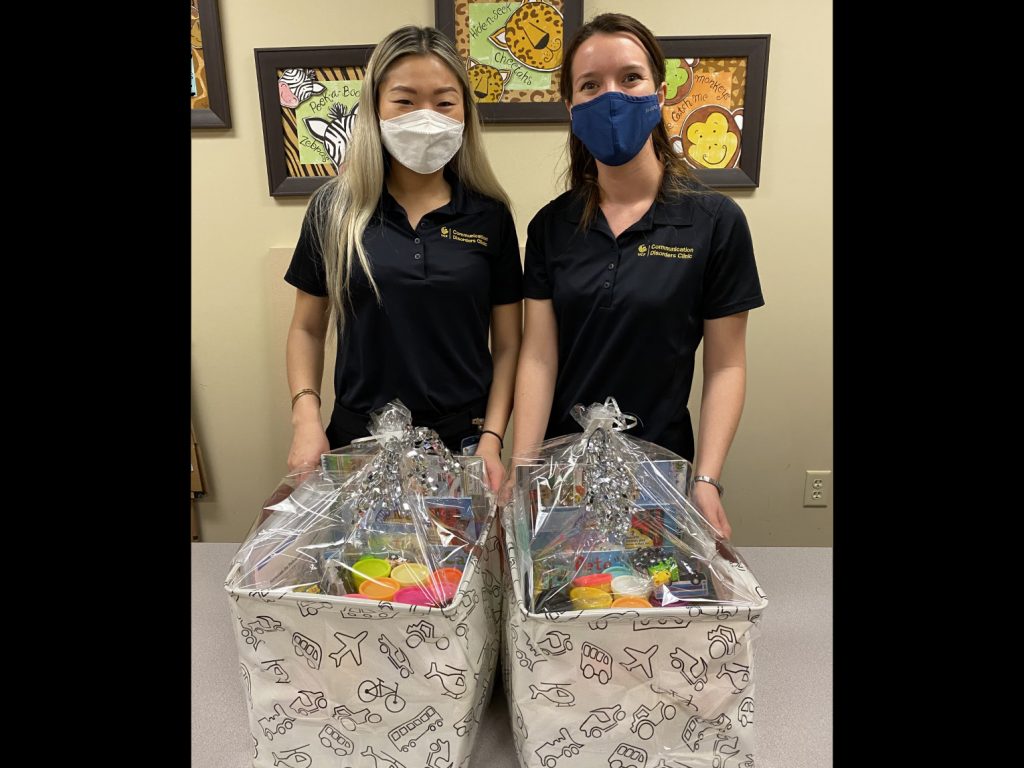 Graduate students Jeena Park and Daniella Lopez showcase the OCPS theme boxes they helped craft.