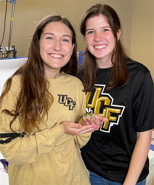 Kaitlyn holding a frog with her roommate, Alee.