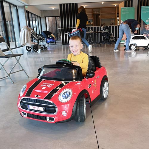 A little boy in a red ride-on toy car.