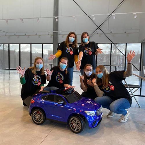A group of volunteers behind an adapted toy car for children.