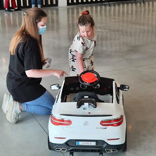 A little girl and a woman check out a white ride-on toy car.