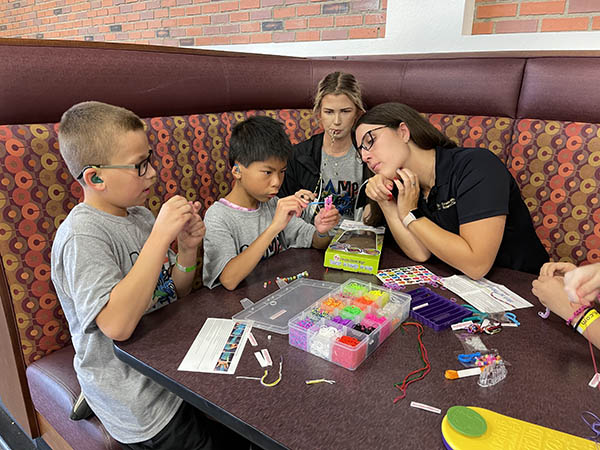 group of campers around a booth making bracelets