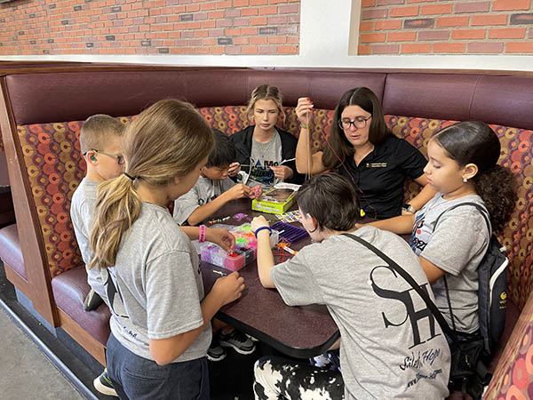 group of campers around a booth making bracelets