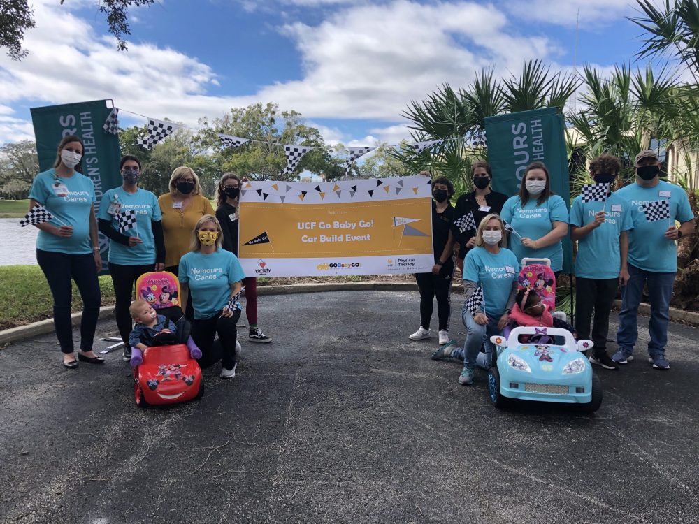UCF Go Baby Go event with young children in toy cars surrounded by parents and professors