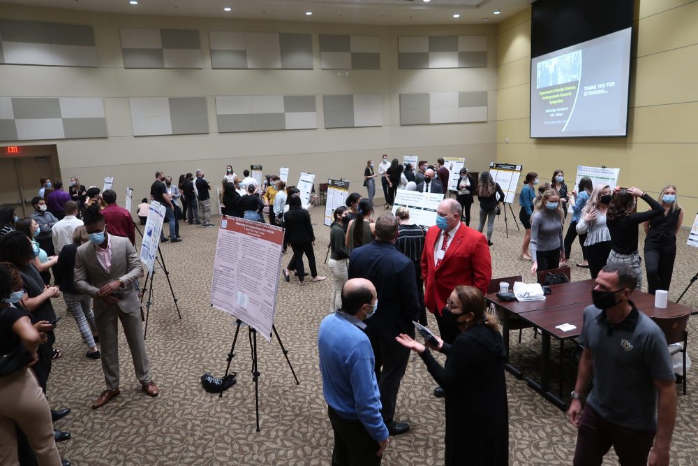 Undergraduate health sciences students showcasing their research proposals at a symposium.