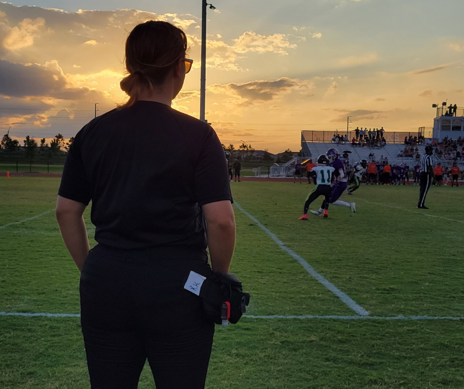 Rebecca Kleckner standing on a field watching men play football.