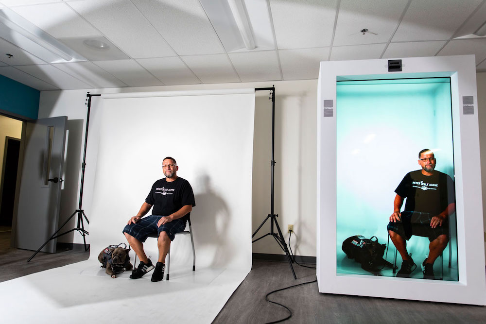 A man sitting against a white background being broadcasted to the hologram machine.