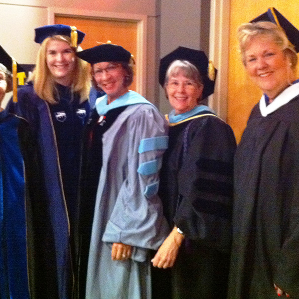 Jennifer Kent-Walsh, Rosa-Lugo, Charlotte Harvey, and Jane Hostetler in cap and gowns.