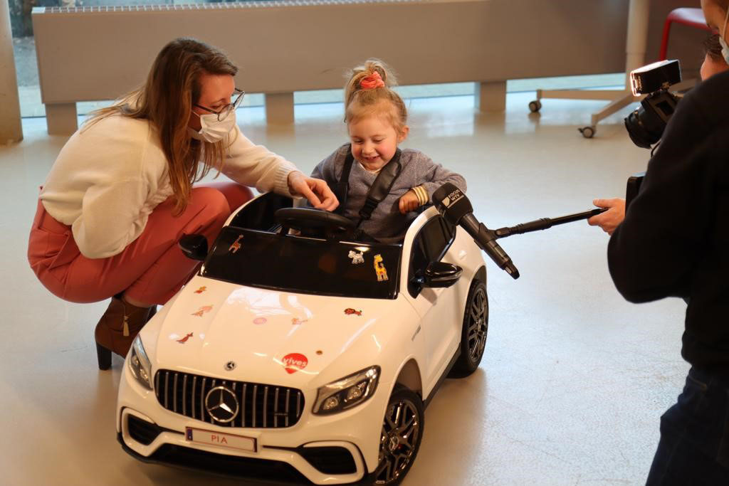 child in toy car with mom