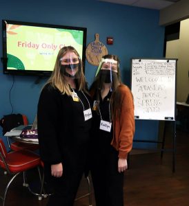 two students with masks standing in front of Aphasia House signs
