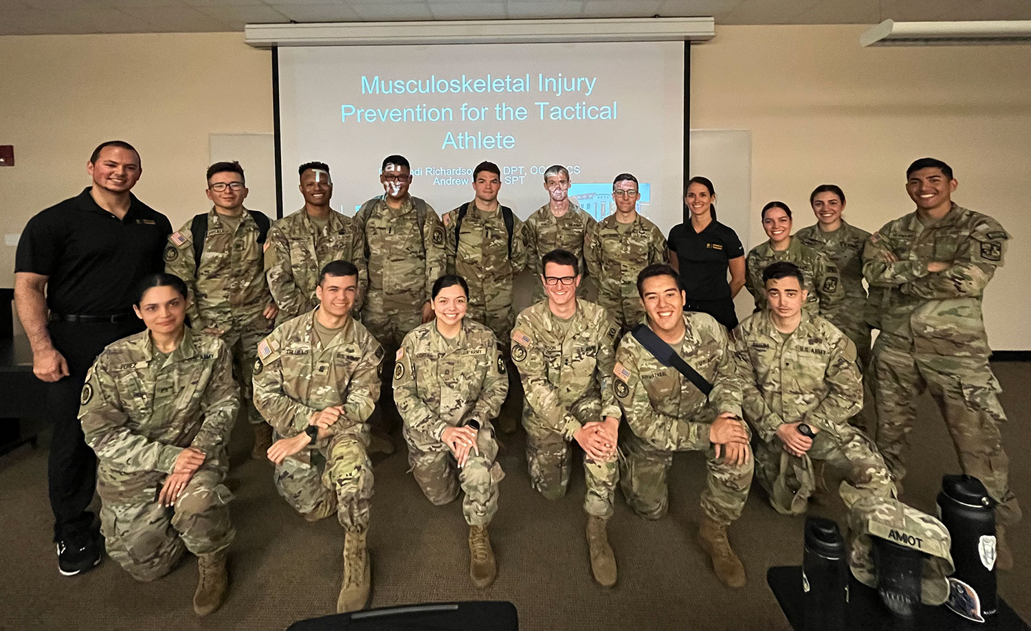 ROTC Cadets, physical therapy professor and student pose in front of presentation titled 