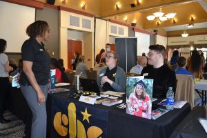 Maxine McGregor standing at agency table talking to two agency representatives