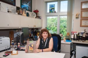 Professor Sophia Dziegielewski seated at her desk holding a journal