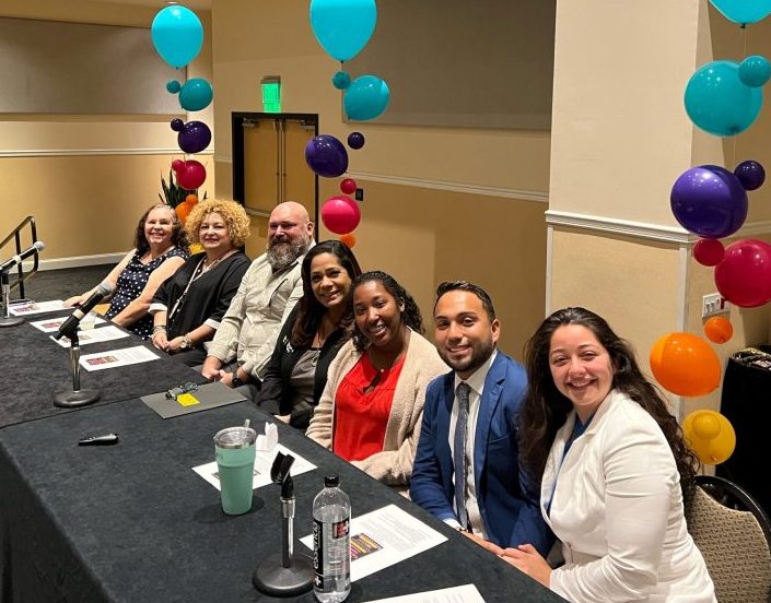 UCF School of Social Work Faculty Olga Molina (far left) with other panelists at event at a table wth balloons around them