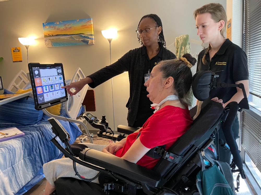two students pointing to a digital device to help a patient