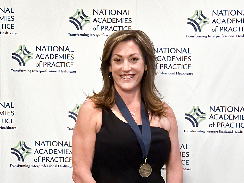 Associate Dean Bari Hoffman standing with a medal around her neck and smiling at the camera