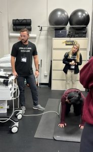 Luk in a weight room, monitoring a research participant on the floor