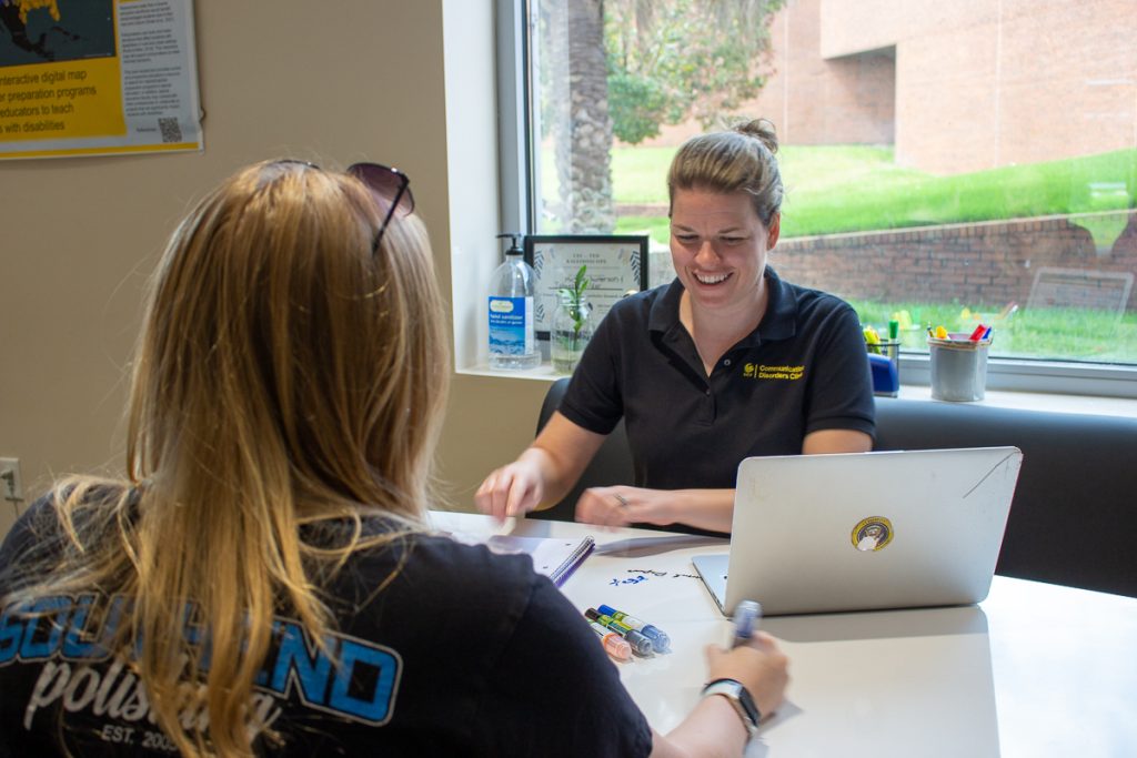 A UCF communication sciences and disorders graduate student clinician with a client.