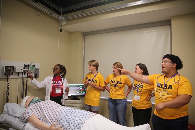 Students in HLSA shirts standing over mannikin