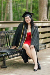 Brooke Martinez on a bench in graduation regalia