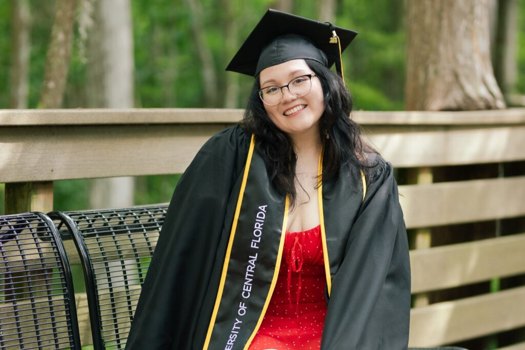 Brooke Martinez on a bench in graduation regalia