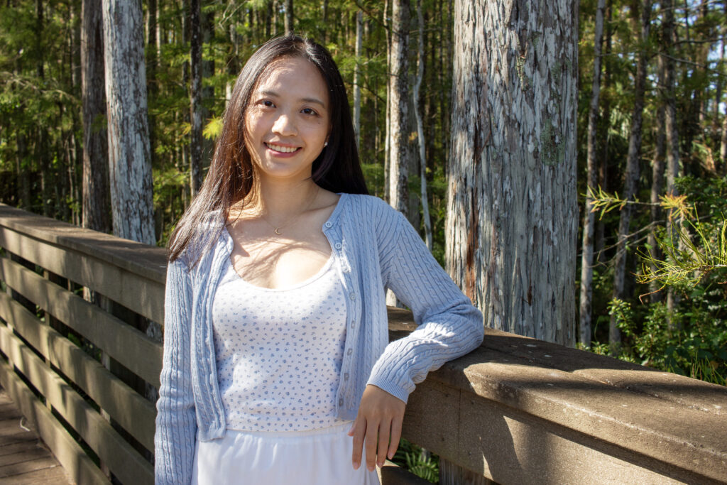 Qianxia Jiang stands on wooden boardwalk in front of trees