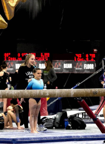 Hannalee assists a young gymnast prepare to mount a balance beam. 