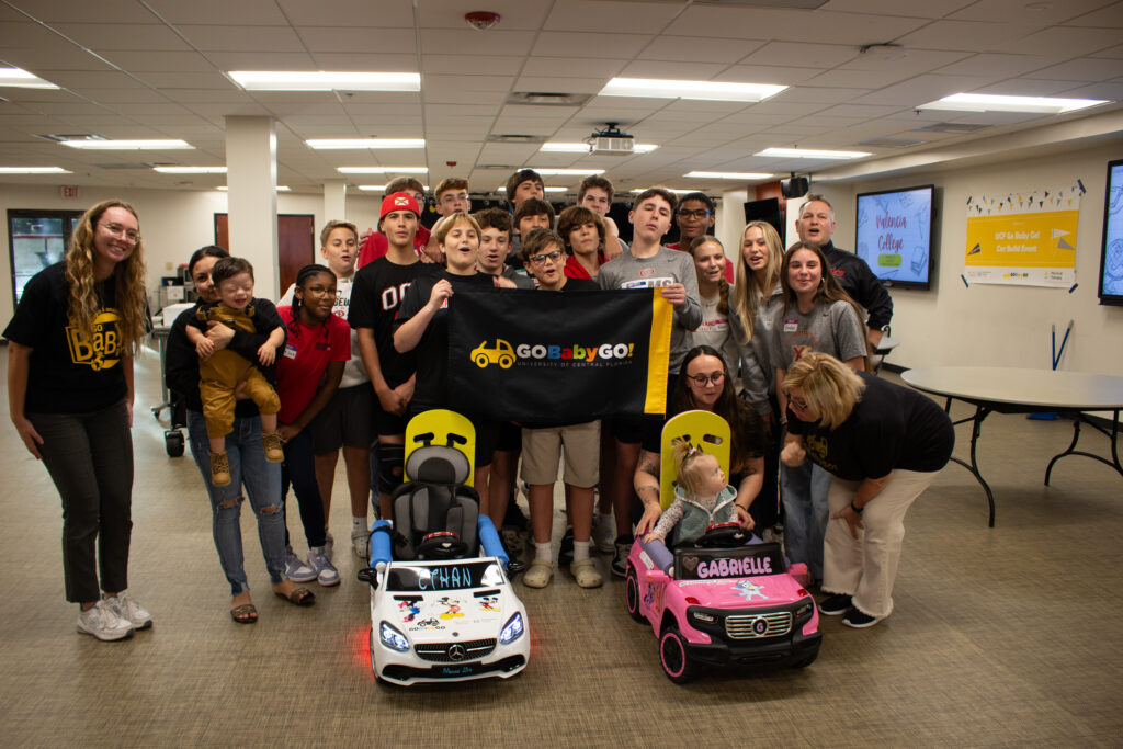 Jennifer Tucker and students from Orangewood Christian smile with two children who received Go Baby Go cars.