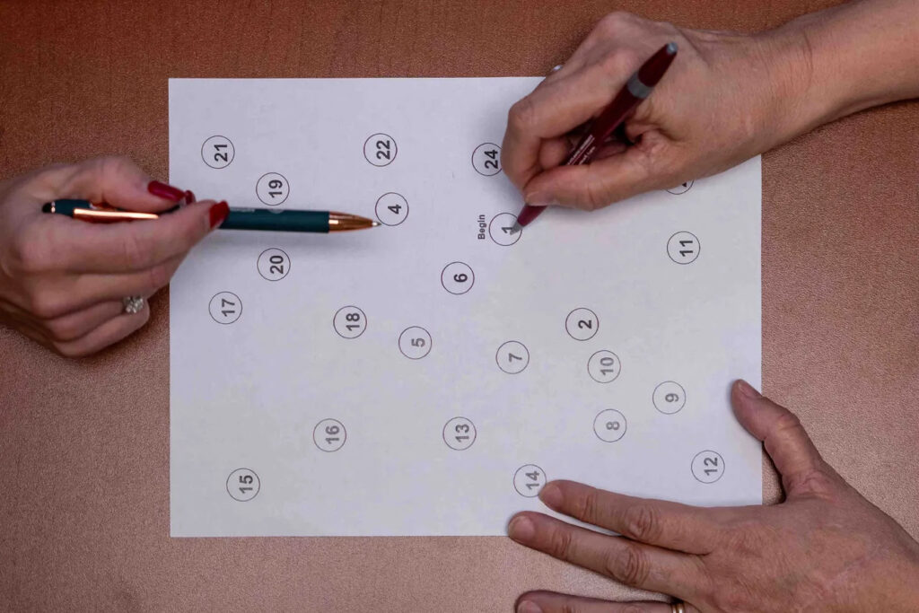 three hands write on a sheet of paper with circles and numbers on it