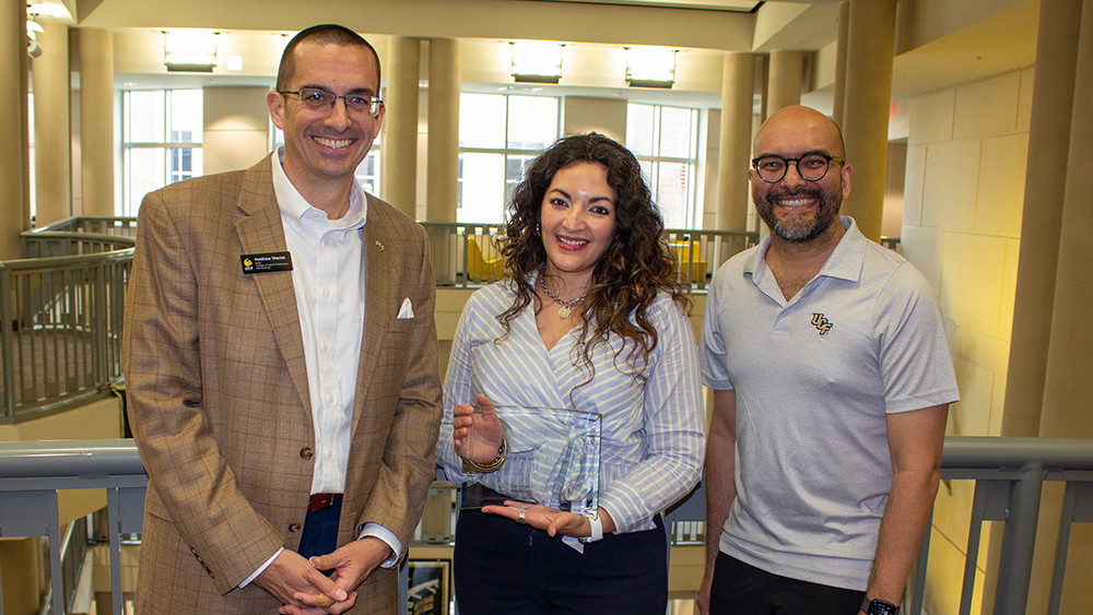 Matthew Theriot, Aimmy De Jesus Rodriguez, and Humberto Lopez Castillo smiling together with Aimmy holding her award