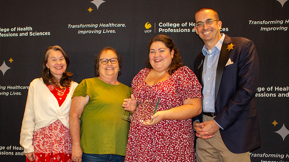 Christine Ferretti, Shelley Hall, Adriana Kelly, and Matthew Theriot smiling together in front of a CHPS background with Adriana holding her award